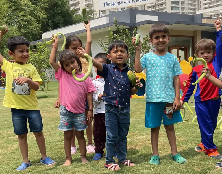 Happy play school children holding plucked vegetables