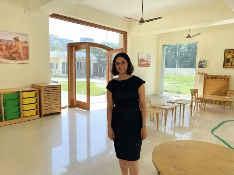 Montessori guide in bright classroom overlooking garden at Productive Minds preschool in Gurgaon.