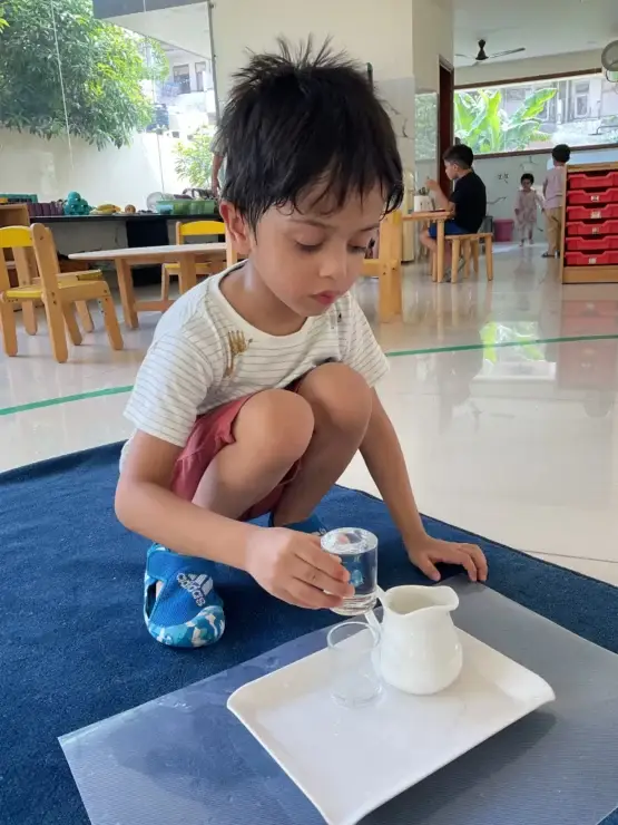 A toddler practicing a practical-life pouring exercise