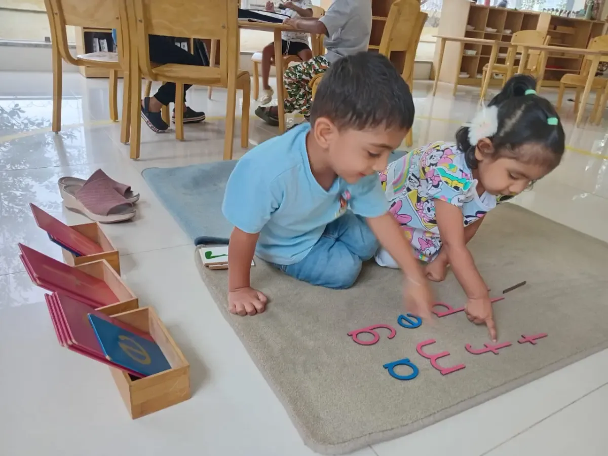 Toddlers collaborating with the Montessori large movable alphabet